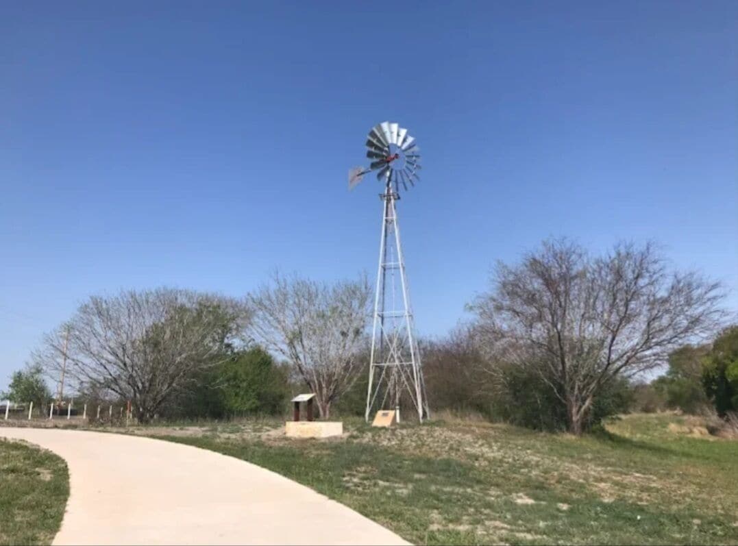 A windmill in a grassy area with a clear sky.