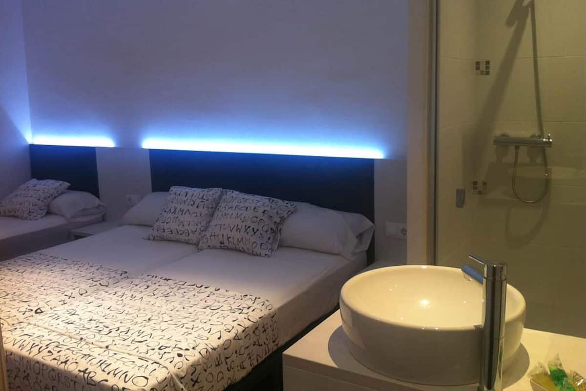 Habitación de hotel con dos camas, un lavamanos grande y redondo, y una ducha.