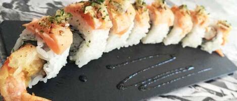 Une assiette de sushis avec des crevettes et du saumon, présentée sur une ardoise noire.