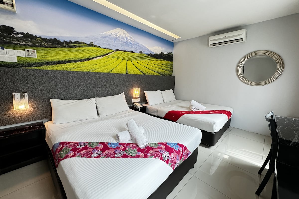 A hotel room with two beds, a mural of a mountain and fields, a round mirror, and a modern design.