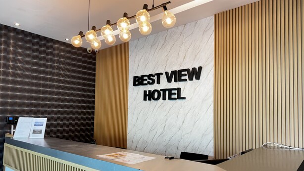 A reception desk with a sign reading "BEST VIEW HOTEL" and a modern design with a marble wall and wooden paneling.
