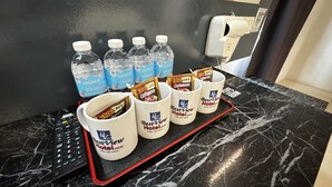 A tray with water bottles, coffee cups, and coffee packets on a marble countertop.