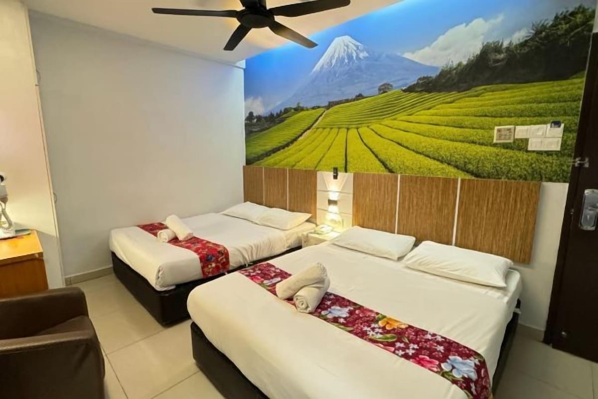 A hotel room with two beds, a ceiling fan, and a mural of a mountain landscape.