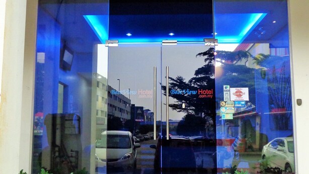 A hotel entrance with a glass door, potted plants, and a sign for Best View Hotel.