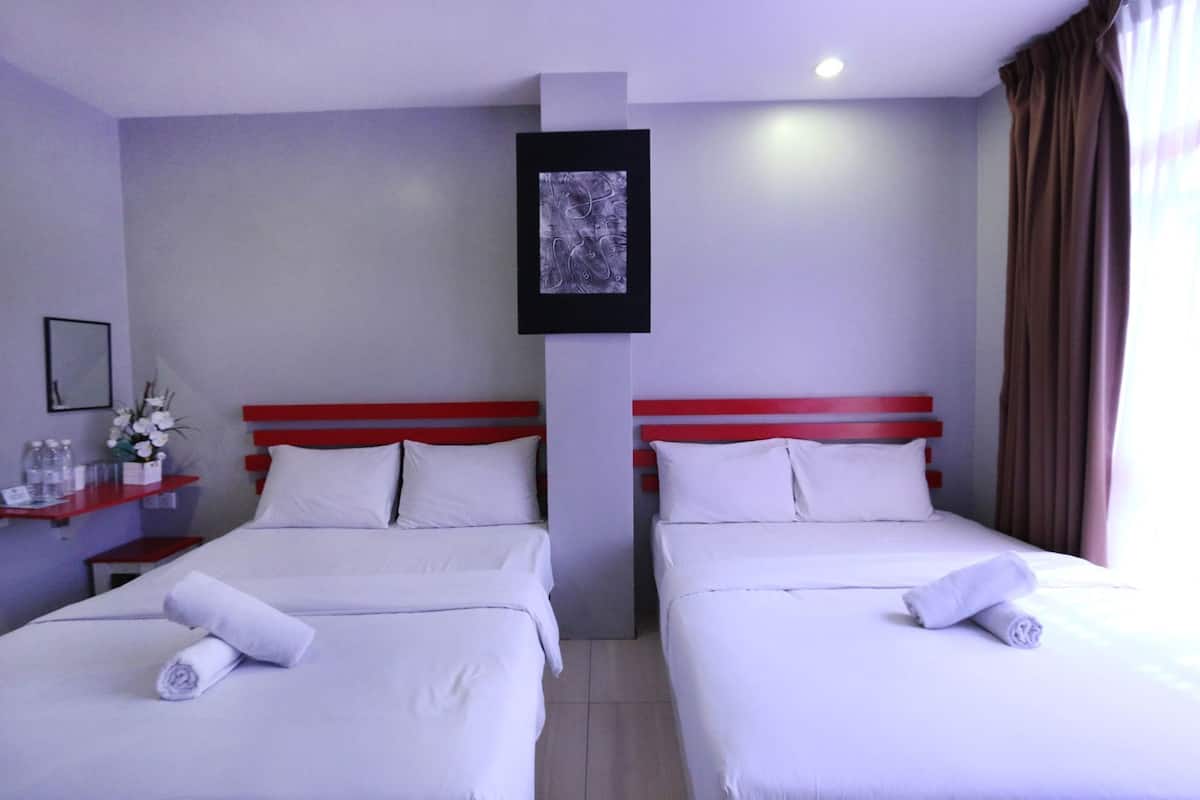 Une chambre d’hôtel avec deux lits, une petite table sur laquelle est posé un vase de fleurs, un tableau encadré au mur et une fenêtre avec des rideaux.