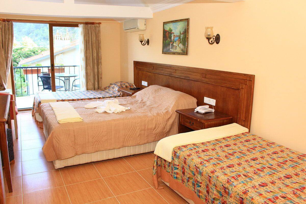 A hotel room with two beds, a balcony with a table and chairs, and a painting on the wall.