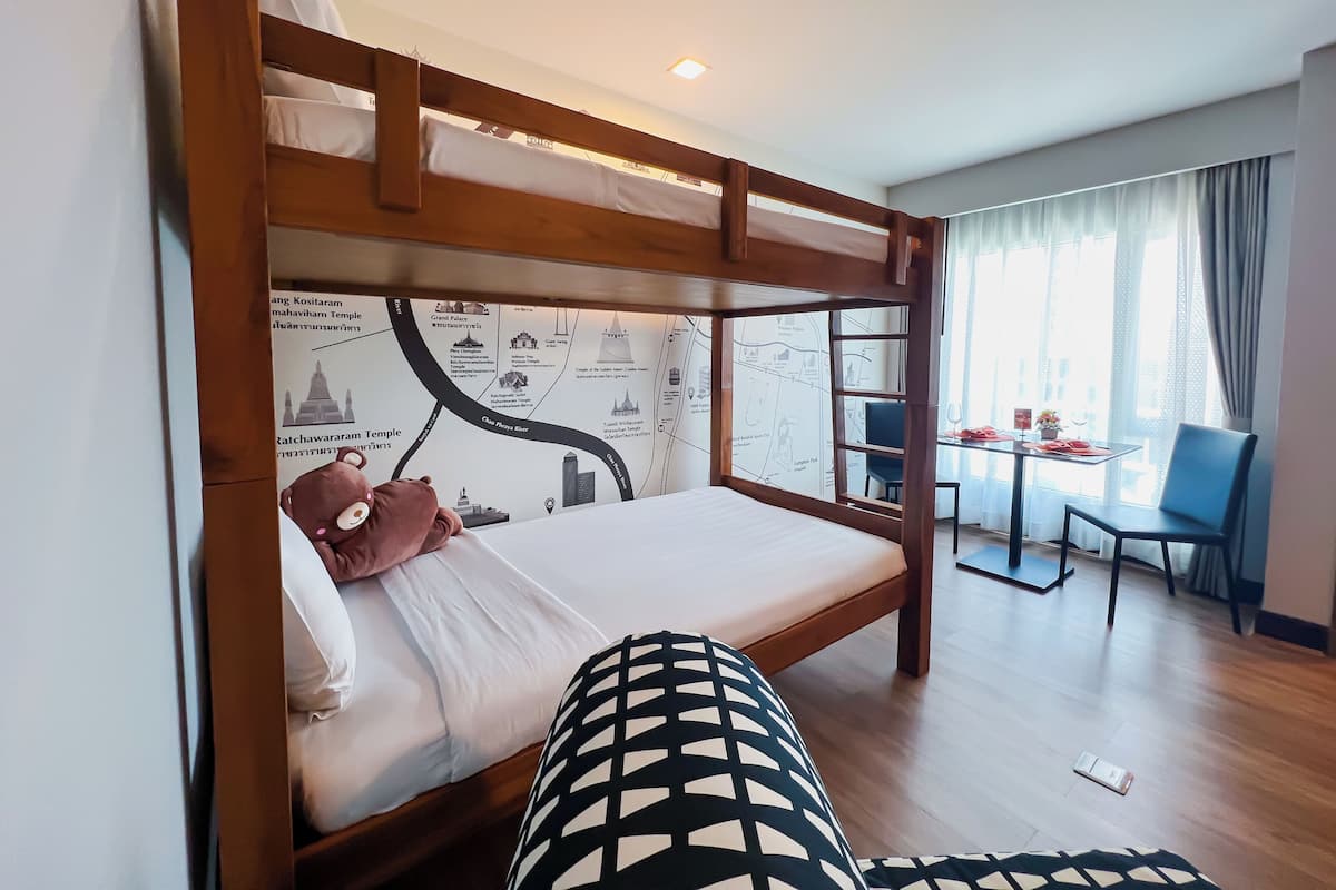 A bunk bed with a map mural, a dining table with chairs, and a view of the room.