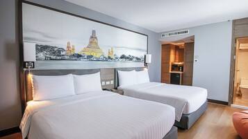 A hotel room with two beds, a painting of a cityscape, a microwave, and a small kitchenette.
