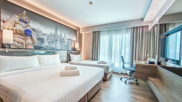 A hotel room with two beds, a desk, a chair, a TV, and a large mural of a temple. - Citrus Sukhumvit 11 Bangkok by Compass Hospitality (Bangkok)