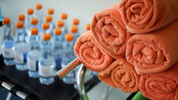 A stack of orange towels and multiple bottles of water on a cart.