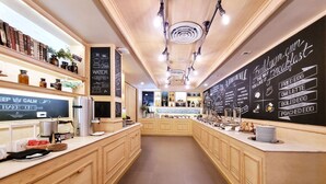 A modern kitchen with wooden cabinets, a central island, and a chalkboard menu. - Citrus Sukhumvit 11 Bangkok by Compass Hospitality (Bangkok)