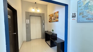 Un vestíbulo de hotel con una recepción, un mapa colgado en la pared y un ascensor.
