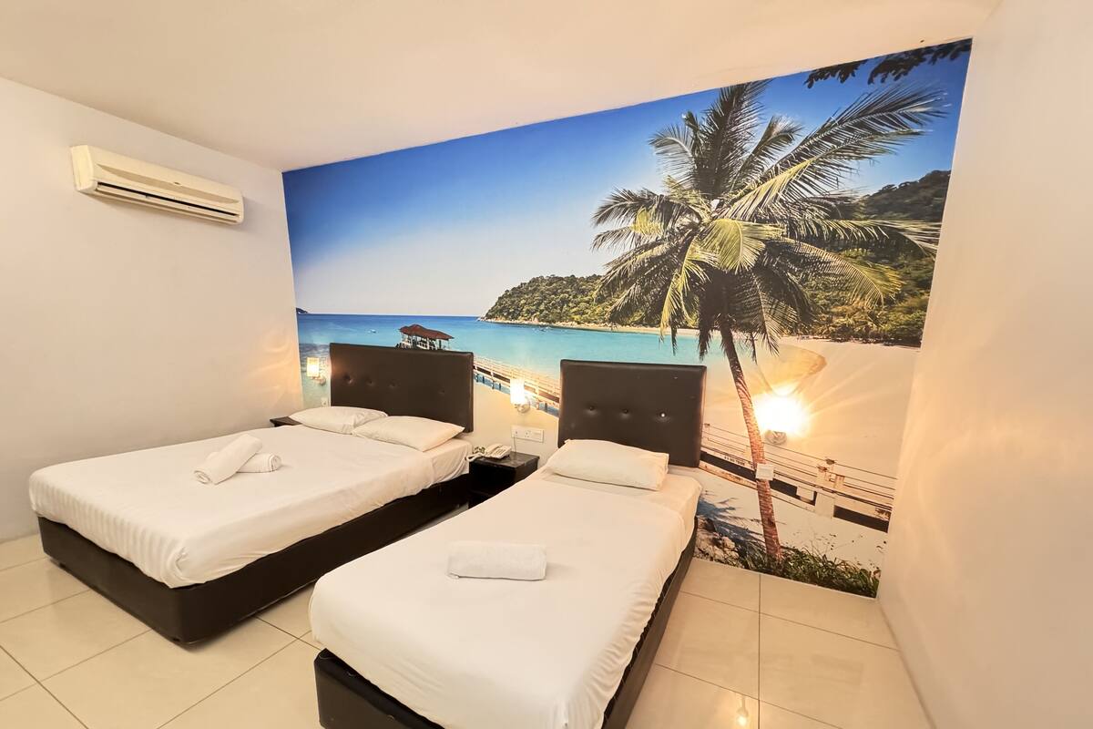 Habitació d'hotel amb dos llits, un mural de platja i un aire condicionat.