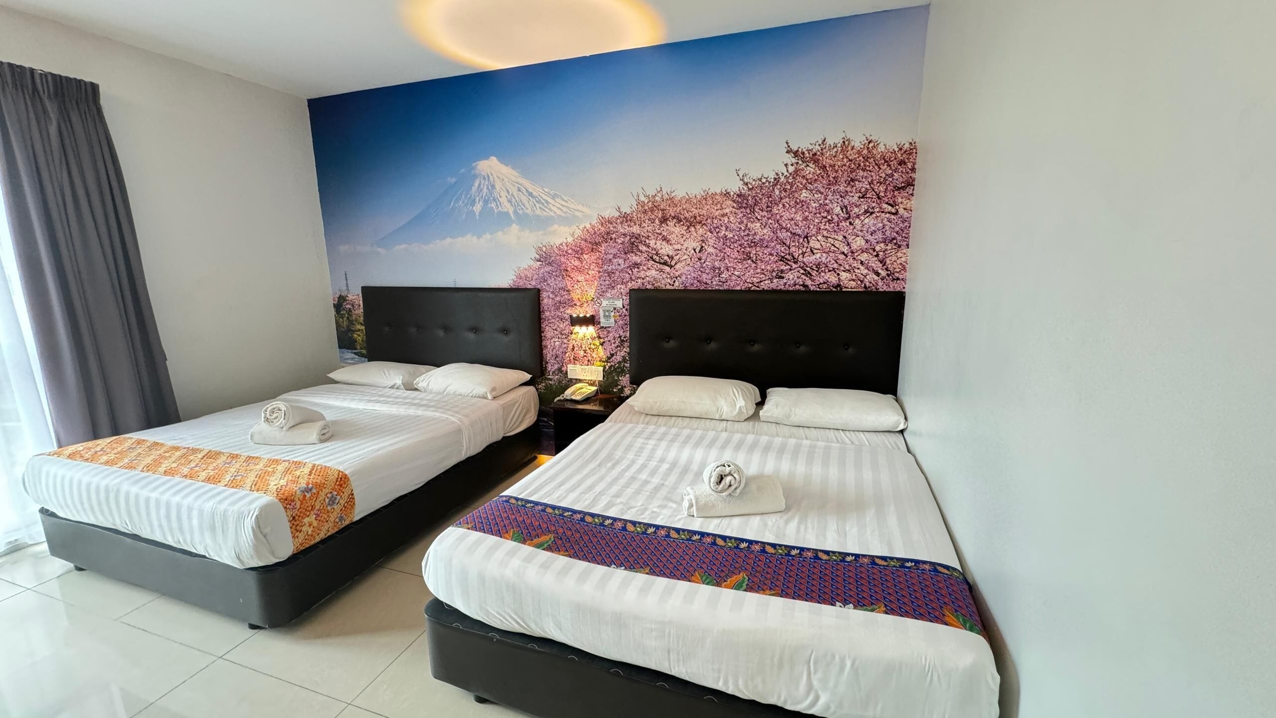 A hotel room with two beds, each with a neatly made bed and a pillow.