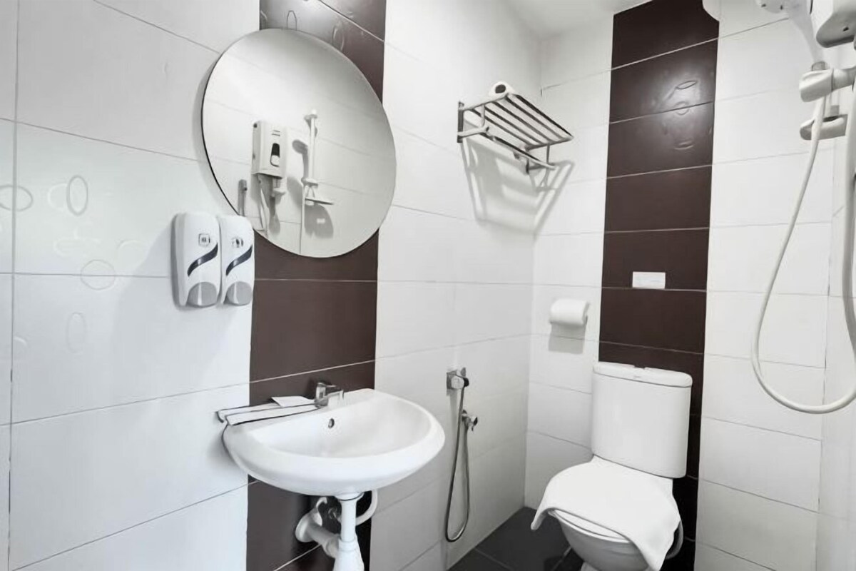 Une salle de bain équipée d’un lavabo, de toilettes, d’un miroir, d’un porte-serviettes et d’une douche.