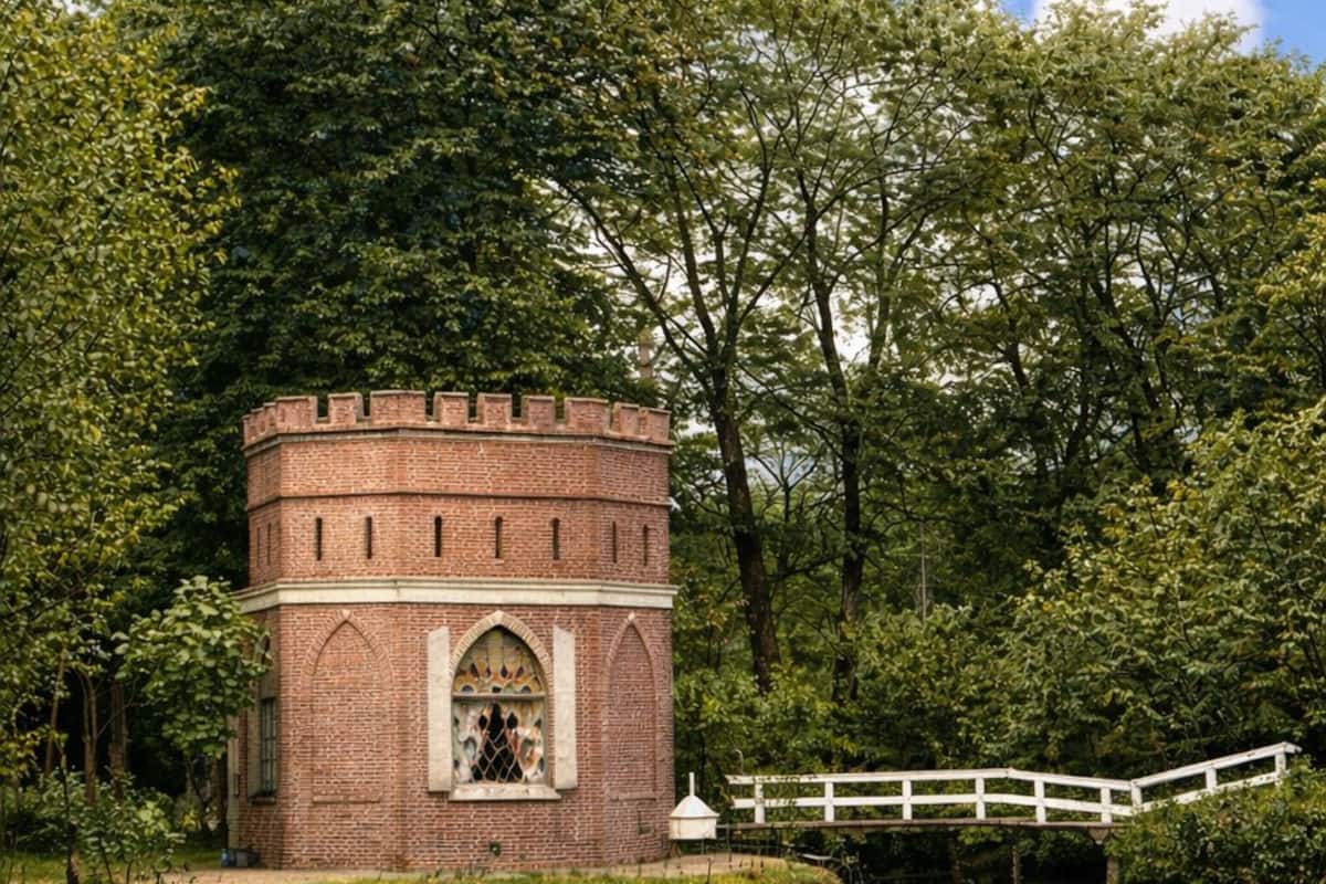 A brick tower with a white fence and a bridge over a body of water.