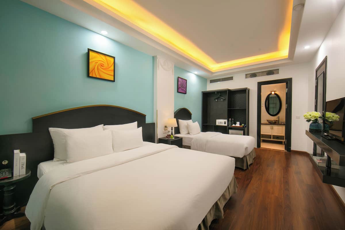 A hotel room with two beds, a desk, a chair, a mirror, and a wardrobe.