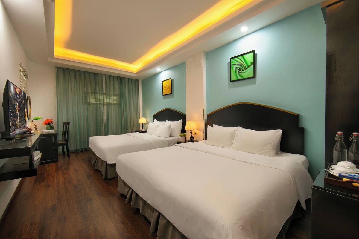 A hotel room with two beds, a desk with a computer, a chair, and a TV.