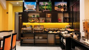 A hotel buffet with a variety of food options, a seating area with chairs, and a wall with decorative items and artwork. - Hanoi Harmonia Hotel & Spa (Hanoi)