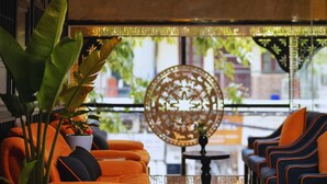 A room with orange sofas, a round decorative table, and a large potted plant. - Hanoi Harmonia Hotel & Spa (Hanoi)