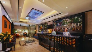 A hotel lobby with a reception desk, seating area, and a large mural on the wall. - Hanoi Harmonia Hotel & Spa (Hanoi)