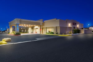 Un hotel con entrada techada, zona de estar al aire libre y aparcamiento.