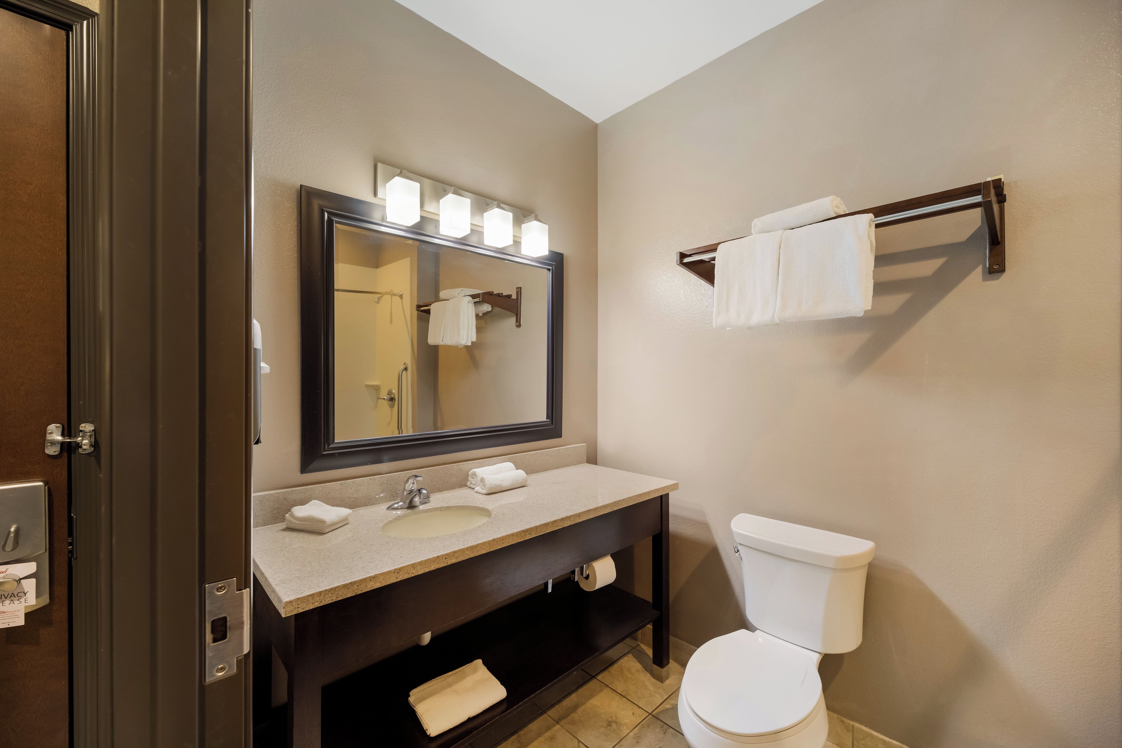 A bathroom with a sink, mirror, towel rack, and toilet.