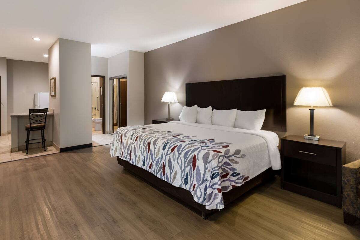 A modern hotel room with a large bed, bedside tables, a desk, and a chair.