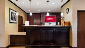 A reception desk with a digital screen displaying "Free Wi-Fi All Rooms" and a clock on the wall. - Red Roof Inn Pecos (Pecos)