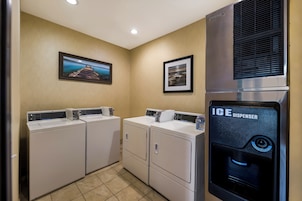A laundry area with two washing machines, an ice dispenser, and two framed pictures on the wall.