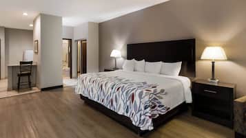 Une chambre d’hôtel avec un grand lit, deux tables de chevet avec des lampes, une chaise et une vue sur la salle de bain.