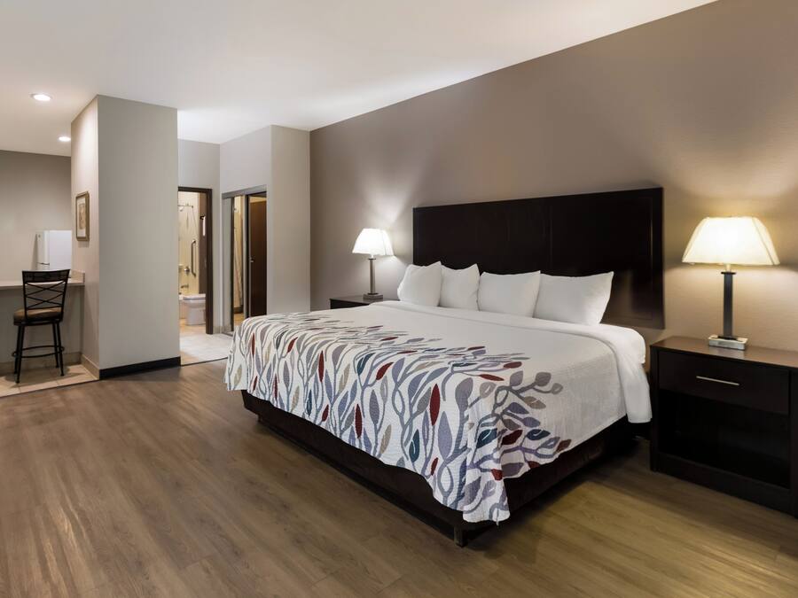 Une chambre d’hôtel avec un grand lit, deux tables de chevet avec des lampes, une chaise et une vue sur la salle de bain.