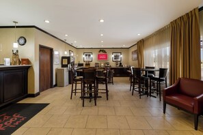 Een hotel lobby met een receptiebalie, een zithoek en een klok aan de muur.
