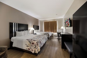A hotel room with a large bed, two bedside tables with lamps, a desk with a chair, a flat-screen TV, and a window with curtains.