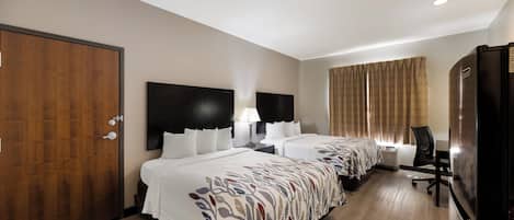 A hotel room with two beds, a wardrobe, a desk, a chair, a television, and a window with curtains.
