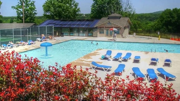 A swimming pool with blue lounge chairs, a small building with a sloped roof, and a fenced tennis court area. - 2 UNITS, Ground Floor, Branson's Pointe Royale, INDOOR POOL, Golf, Sleeps 12 (Branson)