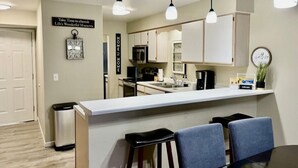 A modern kitchen with a central island, pendant lighting, and a sign that reads "Take Time to cherish Life's Wonderful Moments." - 2 UNITS, Ground Floor, Branson's Pointe Royale, INDOOR POOL, Golf, Sleeps 12 (Branson)