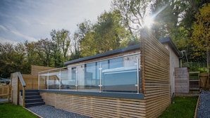 A modern wooden structure with a glass enclosure, a staircase, and a gravel pathway. - Caswell Bay Hide Out - Cabin - Landimore (Swansea)