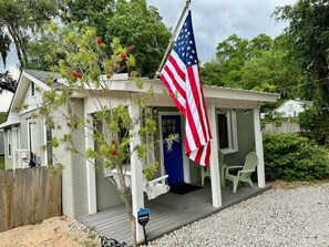 Ein kleines Haus mit Veranda, einer amerikanischen Flagge und einer blauen Tür.