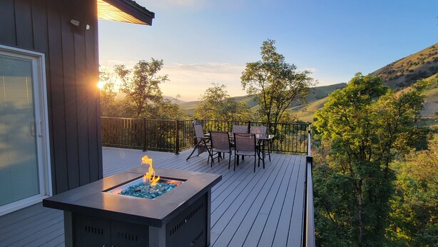 Una terraza con una chimenea, mobiliario exterior y una vista panorámica de colinas y árboles.