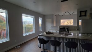 Cocina moderna con ventanas amplias, una isla central con taburetes altos y vistas a un paisaje montañoso.