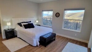 Un dormitorio con cama, mesitas de noche, ventana y vistas al exterior.