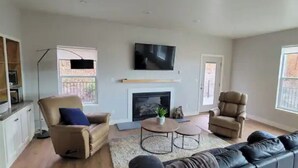 Amplia sala de estar con chimenea, televisor montado encima y un gran ventanal que proporciona luz natural.