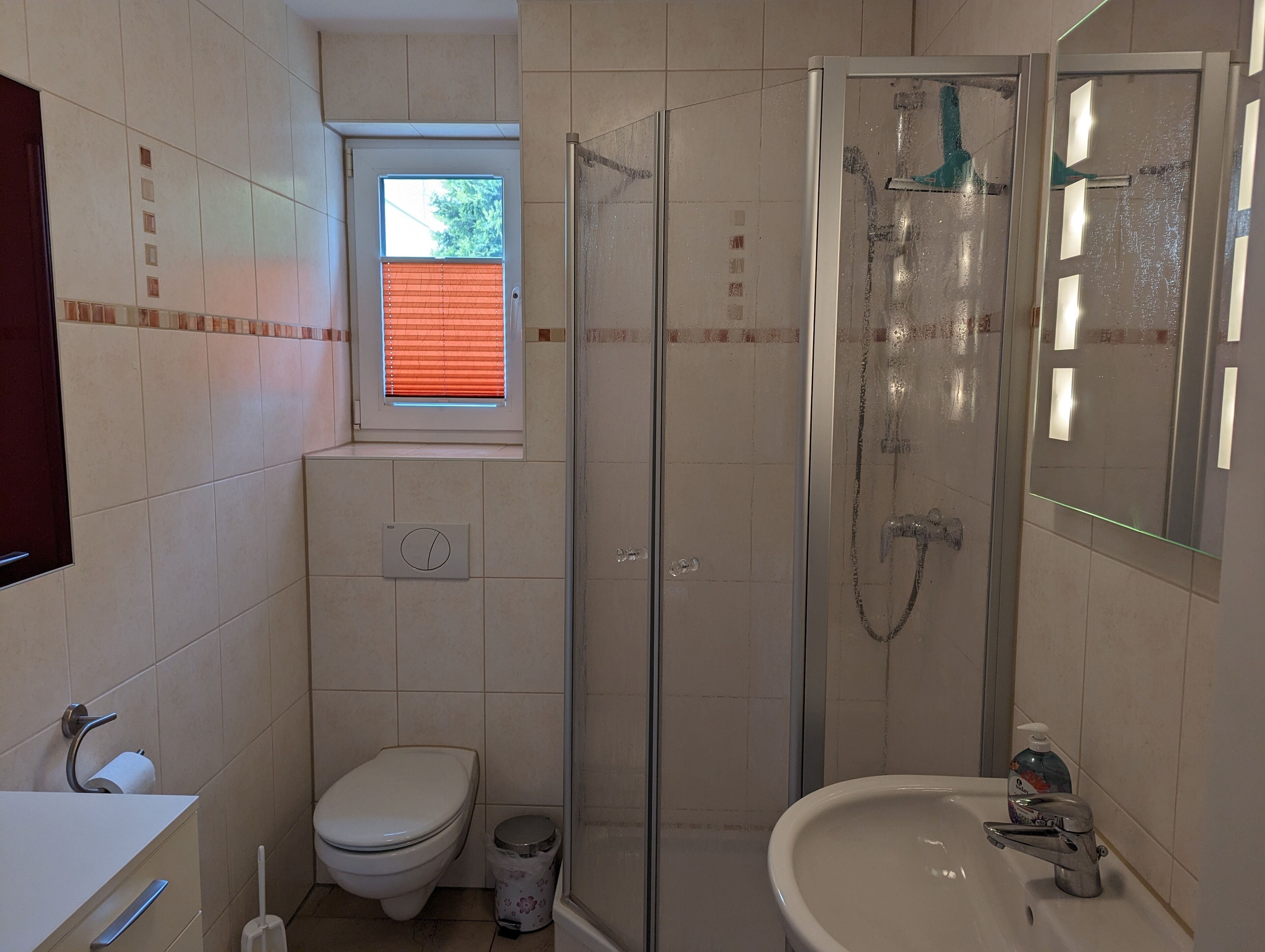 A compact bathroom with a toilet, sink, and glass-enclosed shower.