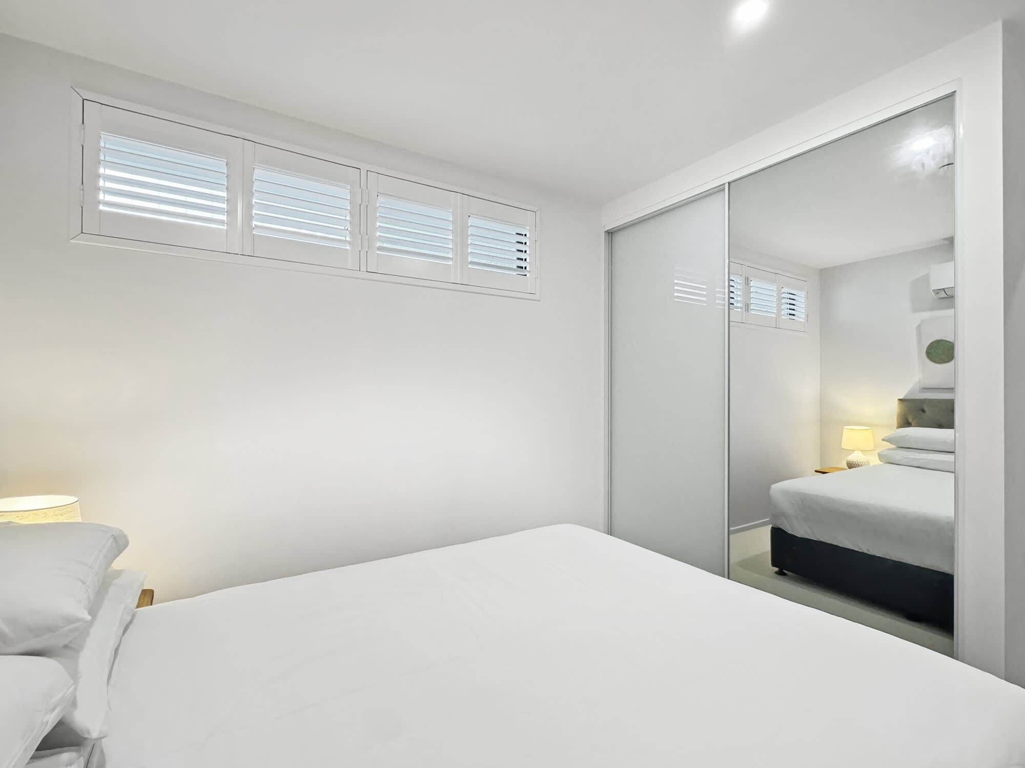Une chambre à coucher au style minimaliste, avec un lit, une table de chevet et un miroir.