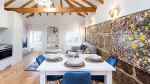 Un coin repas avec une table blanche dressée pour quatre personnes, entourée de chaises bleues.