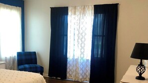 Una camera d'albergo con un letto, una sedia, una scrivania e una finestra con tende.