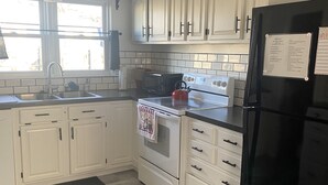 A kitchen with white cabinets, a black refrigerator, a stove, and a microwave.