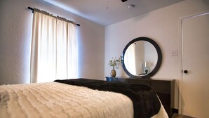 Un dormitorio con cama, cómoda, espejo y puerta.