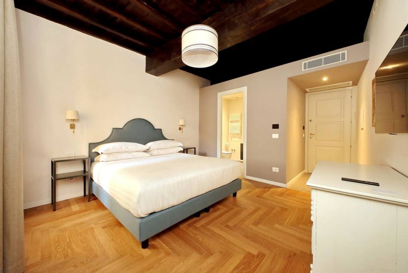 Een slaapkamer met een bed, nachtkastjes, een kledingkast en een plafondlamp.